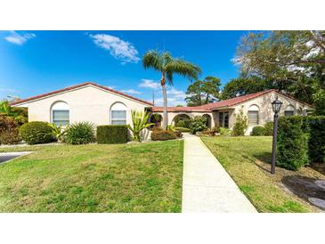 Charming single-story home featuring a well-manicured lawn, vibrant landscaping, and a welcoming walkway to the entrance at 2259 Pueblo Ln # V38, Sarasota, FL 34231
