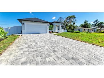 Beautiful home featuring a long, patterned driveway and a well-manicured lawn under a clear blue sky at 380 Holly Rd, Venice, FL 34293