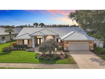 Beautiful home with a well-manicured lawn, tile roof, mature trees, and an attached two car garage at 1447 Gleneagles Dr, Venice, FL 34292