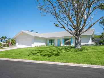 Charming single-story home with a well-manicured lawn, mature tree, and white exterior paint at 172 Sea Anchor Dr, Osprey, FL 34229