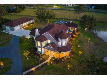 Stunning aerial view of an estate home with a barn, screened pool, pond, and lush landscaping all around at 19006 69Th E Ave, Bradenton, FL 34211
