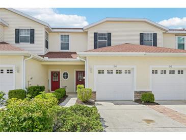 Inviting two-story townhouse with attached garage, manicured landscaping, and brick-lined driveway at 2353 Rosewood Ln, North Port, FL 34289