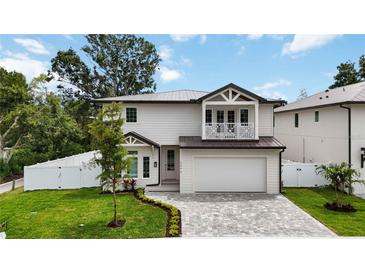 Charming two-story home with a well-manicured lawn, gray brick drive and white exterior at 2596 Floyd St, Sarasota, FL 34239