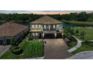 Elegant two-story home with a tile roof, paver driveway and three-car garage, located on a waterfront lot at 2806 Starwood Ct, Lakewood Ranch, FL 34211