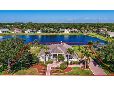 Stunning aerial view of lakeside home with mature landscaping, brick drive, and a defined property line outlined in red at 2816 88Th E Ave, Parrish, FL 34219