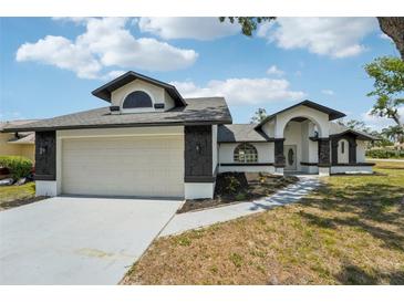 Charming single-story home featuring a two-car garage, arched entry and manicured lawn on a sunny day at 4265 Hoffman Ave, Spring Hill, FL 34606
