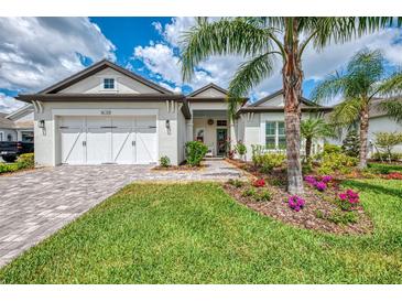 Charming home featuring a well-manicured lawn, landscaped flower beds, and a brick driveway leading to a two-car garage at 749 Tailwind Pl, Sarasota, FL 34240