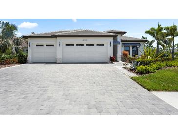 Beautiful home exterior with a three-car garage and manicured landscaping at 8229 Grande Shores Dr, Sarasota, FL 34240