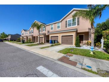A row of tan townhouses with brown shutters and garage doors lined with palm trees, and a fire hydrant in front at 1033 Grantham Dr, Sarasota, FL 34234