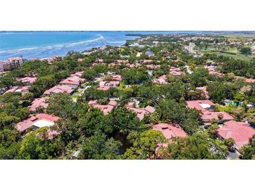 Aerial view of a residential community with lush greenery, mature trees, and a glimpse of a nearby body of water at 3605 Quail Hollow Ln, Bradenton, FL 34210