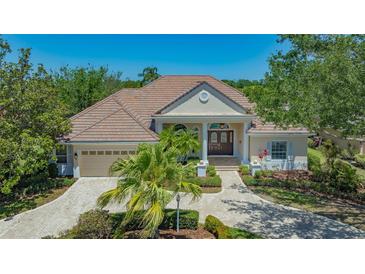 Elegant single-story home with a clay tile roof, manicured landscaping, and a paved driveway at 6633 The Masters Ave, Lakewood Ranch, FL 34202