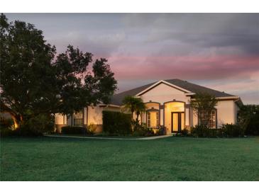 Inviting single-story home with a lush lawn and manicured landscaping, beautifully lit at dusk at 8121 Snowy Egret Pl, Bradenton, FL 34202