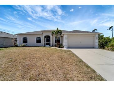 Charming single-story home featuring a two-car garage, arched windows, and tropical landscaping in the front yard at 11 Lateen Sail Dr, Placida, FL 33946