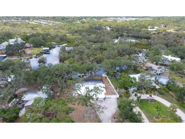 Aerial view of home surrounded by lush landscape; view of private dock, canal access, and serene backyard at 1130 Mill Creek Rd, Bradenton, FL 34212