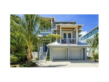 Charming two-story home with a two-car garage, beautiful landscaping, and a cozy balcony on a sunny day at 212 Spring Ave, Anna Maria, FL 34216