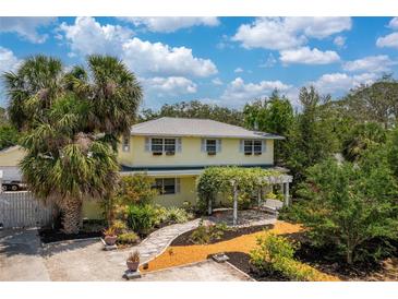 Charming two-story home with a pergola, landscaped yard, and mature palm trees at 2165 Lemon Ave, Englewood, FL 34223