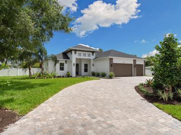 Beautiful home with a three-car garage and a circular driveway, surrounded by lush greenery and a blue sky at 2319 Webber St, Sarasota, FL 34239