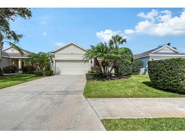 Well-maintained home with a two-car garage, lush landscaping, and a concrete driveway under a bright blue sky at 5238 Aqua Breeze Dr, Bradenton, FL 34208