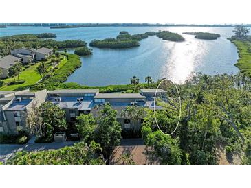 Scenic aerial view of a waterfront condo complex surrounded by lush greenery and sparkling water at 1617 Bayhouse Ct # 121, Sarasota, FL 34231