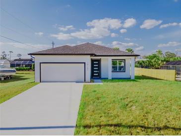 Charming single-story home featuring a clean white exterior, attached garage, and well-maintained lawn at 18182 Steele Ave, Port Charlotte, FL 33948