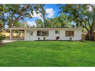 Charming single-story home featuring a well-manicured lawn, a covered carport, and a freshly painted exterior at 2535 Floyd St, Sarasota, FL 34239