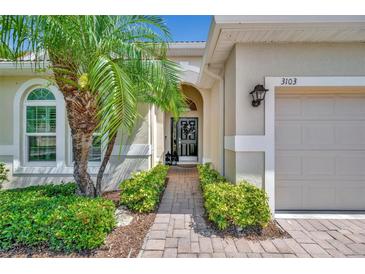 Inviting front entrance featuring a brick walkway, lush landscaping, and a charming palm tree at 3103 77Th E Dr, Sarasota, FL 34243