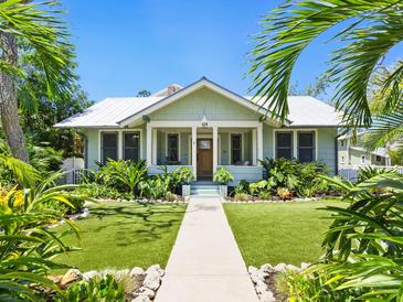 Charming home featuring a manicured lawn, inviting front porch, and lush tropical landscaping at 324 Julia Pl, Sarasota, FL 34236