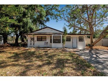 Charming single-story home featuring a classic white facade surrounded by mature trees at 4918 Lahaina Dr, Sarasota, FL 34232