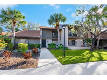 Charming home exterior featuring lush landscaping, mature palm trees, and a well-maintained lawn at 928 Sunridge Dr # F2, Sarasota, FL 34234