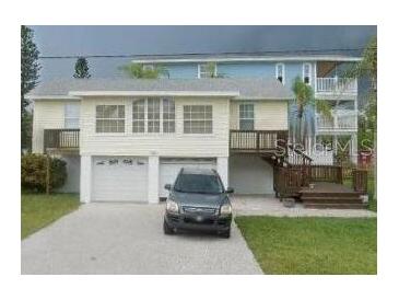 Two-story home featuring a two car garage, wood stairs, and a well-manicured lawn at 300 N 22Nd St, Bradenton Beach, FL 34217
