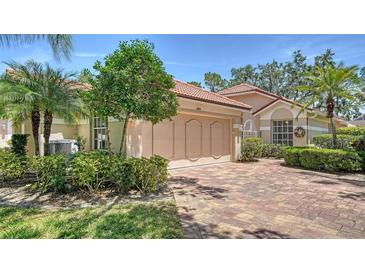 Charming single-story home with a well-manicured lawn, mature trees, and a brick driveway leading to a two-car garage at 3984 Lyndhurst Ct, Sarasota, FL 34235