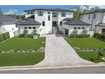 Stunning new construction home featuring a modern design, manicured lawn, and elegant paver driveway at 4815 W Sunset Blvd, Tampa, FL 33629