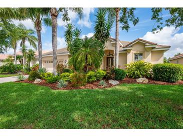 Charming single-story home featuring lush tropical landscaping, a barrel tile roof, and a front-entry two-car garage at 4912 Sabal Lake Cir, Sarasota, FL 34238