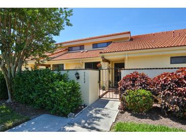 Charming one-story home with a red tile roof, a small courtyard, and mature landscaping at 5362 Huntingwood Ct # 16, Sarasota, FL 34235