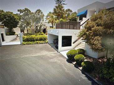Modern condo featuring a private carport with parking space and lovely tropical landscaping surrounding the property at 609 Bayport Way # 609, Longboat Key, FL 34228