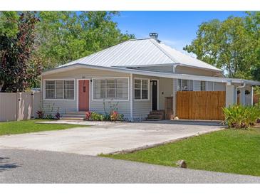A quaint single-story home features a metal roof, long concrete driveway, and lush, well-maintained lawn at 815 Hand Ave, Sarasota, FL 34232