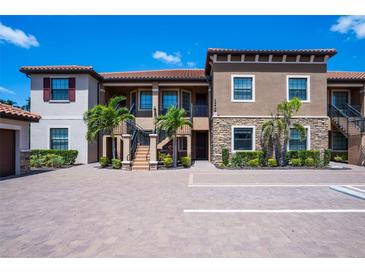 Stunning two-story condo showcasing lush landscaping, two-car parking, and a stylish facade under a clear blue sky at 12409 Osorio Ct # 102, Sarasota, FL 34238