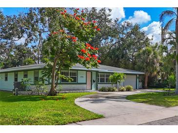 Charming single-story home with a circular driveway and mature landscaping, enhanced by a colorful flowering tree at 1773 South Dr, Sarasota, FL 34239