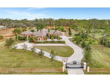 Elegant estate home with a gated entrance, circular driveway, and lush landscaping at 24705 83Rd E Ave, Myakka City, FL 34251