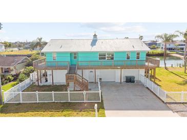 Charming waterfront home with a metal roof, a large deck, and a white picket fence at 3416 Crape Myrtle Dr, Hernando Beach, FL 34607