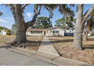 Inviting single-story home featuring mature trees, decorative stone accents and a quaint front entrance at 3941 Pin Oaks St, Sarasota, FL 34232
