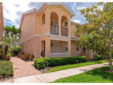 Inviting two-story townhome featuring a charming front porch and balcony, complemented by lush landscaping at 5388 Davini St, Sarasota, FL 34238