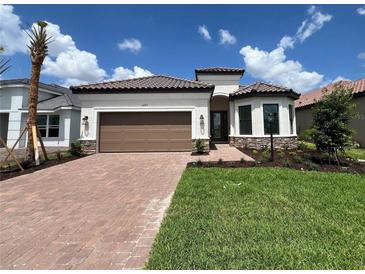 Beautiful single-story home featuring a brick-paved driveway, a brown two-car garage door, and well-manicured landscaping at 6203 Grandview Hill Ct, Bradenton, FL 34203