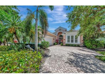 Elegant single-story home with lush landscaping, brick driveway, and a two-car garage at 7624 Boltons Ct, Bradenton, FL 34201