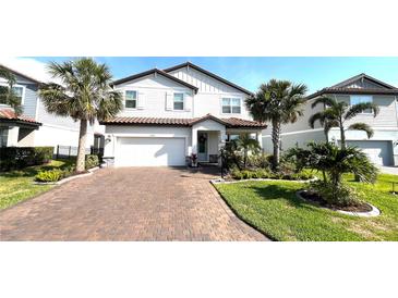Charming two-story home with a brick driveway, lush landscaping, and a two-car garage at 13422 Flat Woods Ter, Bradenton, FL 34211