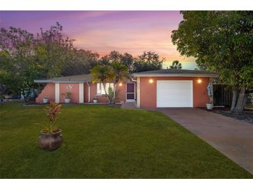 Charming single-story home with a well-manicured lawn and a cozy, inviting facade at sunset at 1434 Beacon Dr, Port Charlotte, FL 33952
