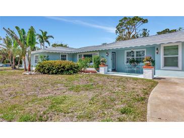 Charming blue home with tropical landscaping, inviting porch, and manicured front yard at 1722 Hazelwood St, Sarasota, FL 34231