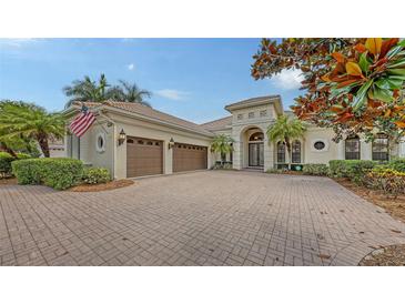 Stately home with a paver driveway, a three-car garage, and lush landscaping at 6919 Dominion Ln, Lakewood Ranch, FL 34202