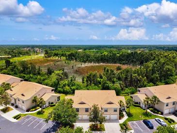 Beautiful aerial view of the townhomes with a large pond and lush green trees behind the homes at 7039 Strand Cir # 34-201, Bradenton, FL 34203