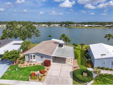 Charming waterfront home featuring lush landscaping and a covered carport on a sunny day at 8439 Imperial Cir, Palmetto, FL 34221